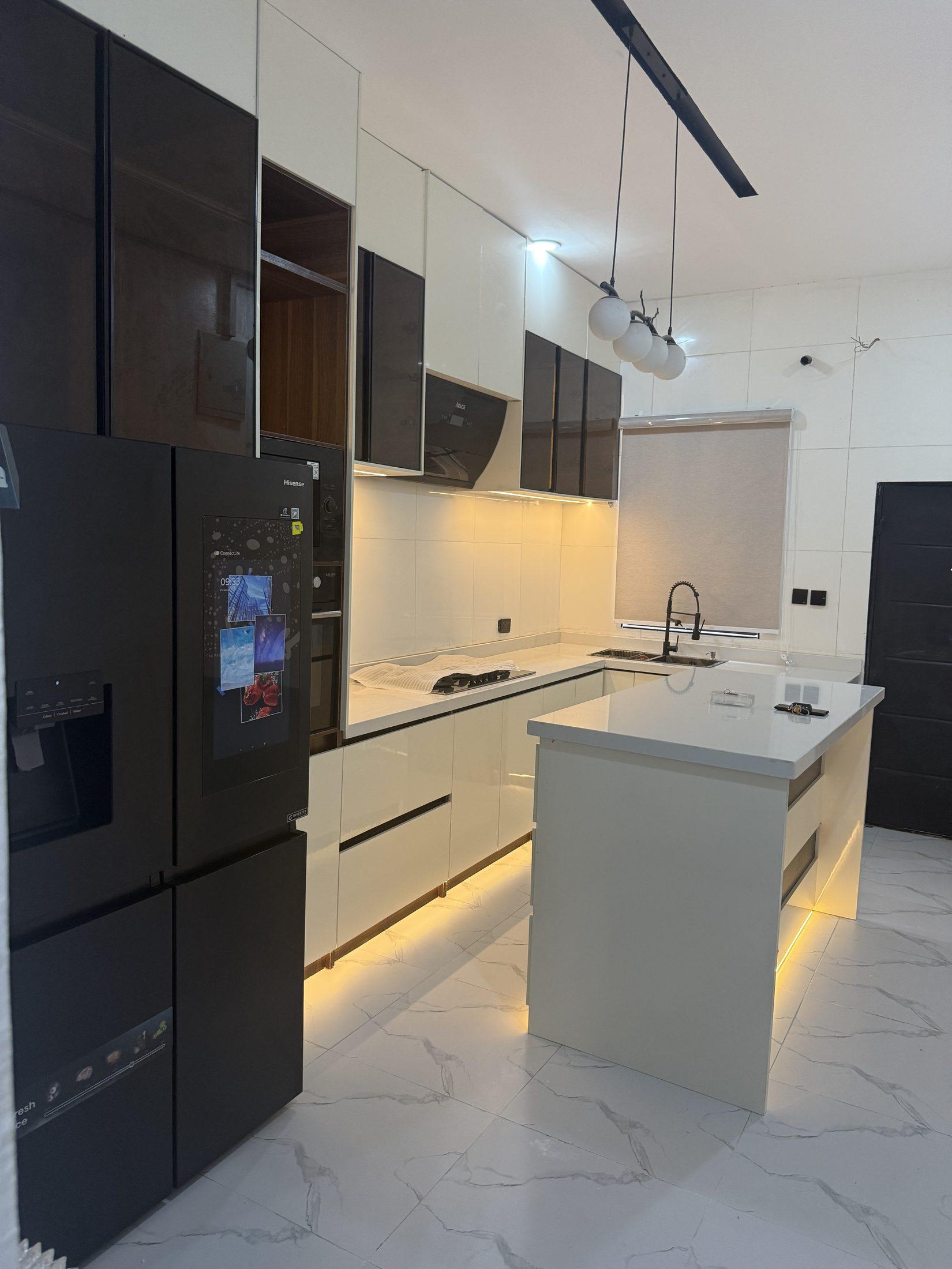Cream gloss kitchen with smoked glass wall units, globe pendants and a lit island
